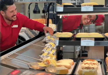 a woman smiling at a conveyor belt